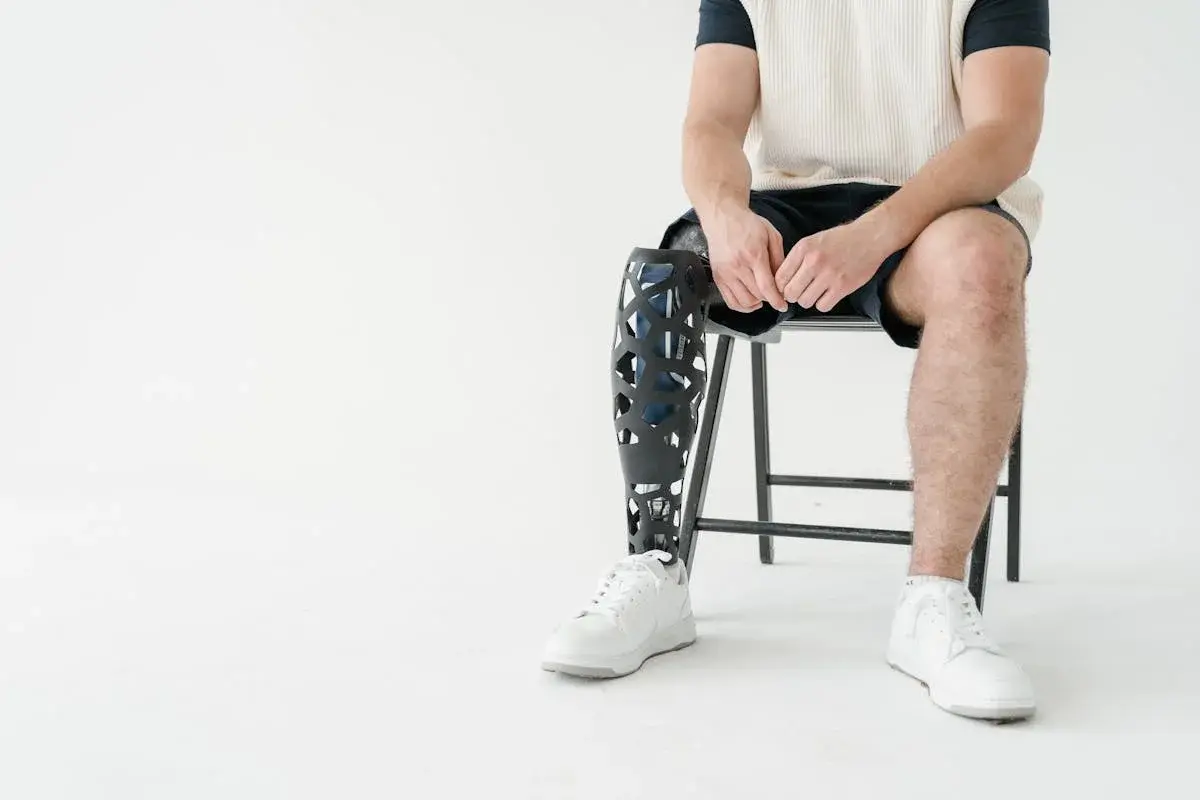 A man with a below-knee prosthetic leg sitting and adjusting his prosthetic socket, showing the interface between the liner and the outer structure