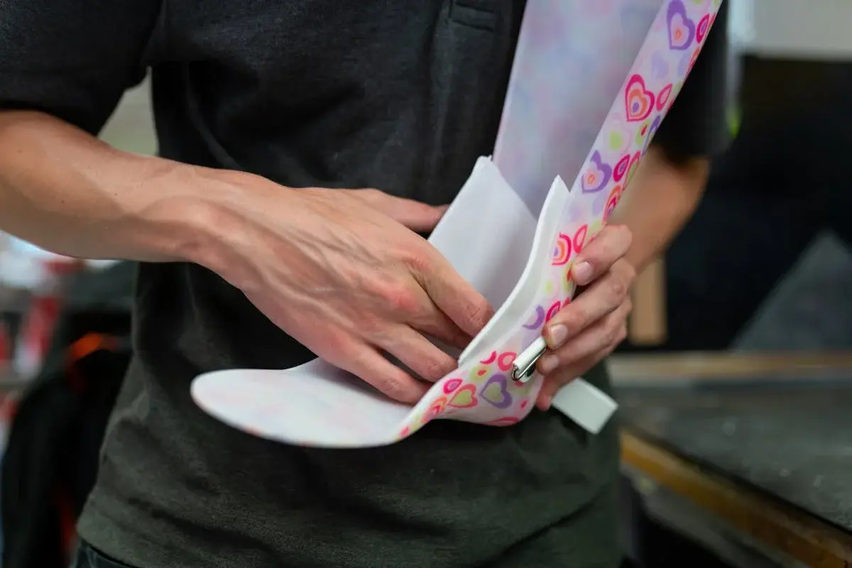 An orthotist designing and marking a custom colourful ankle-foot orthosis during the fabrication process